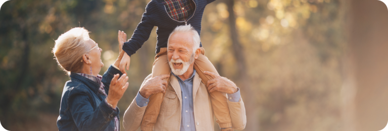 grandmother and grandfather with grandchild on shoulders